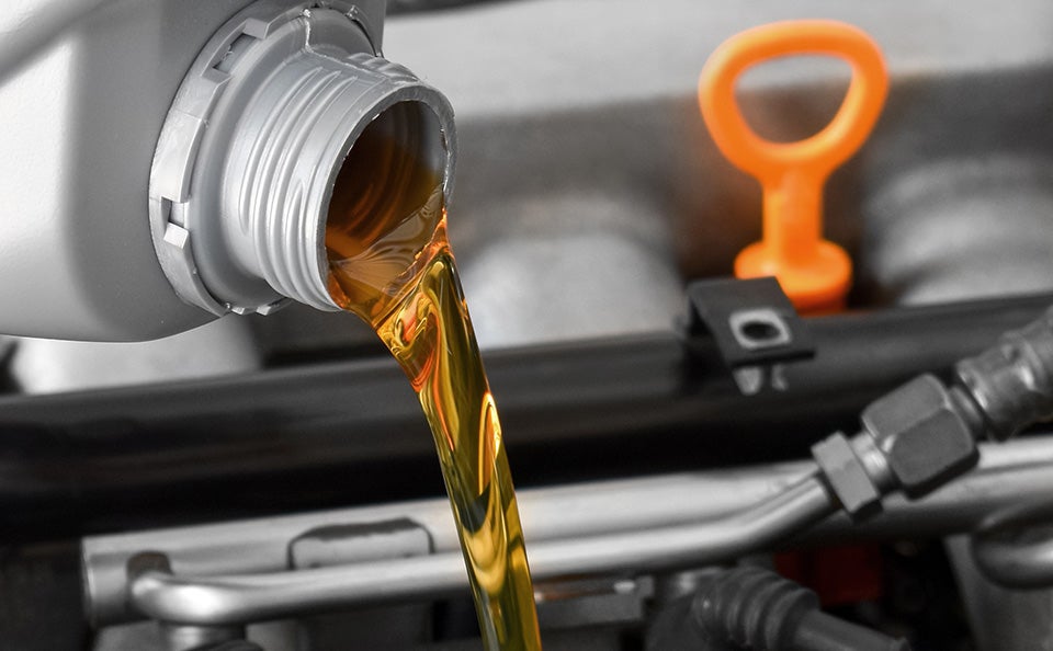 Close-up view of motor oil being poured into a vehicle engine during an oil change service.