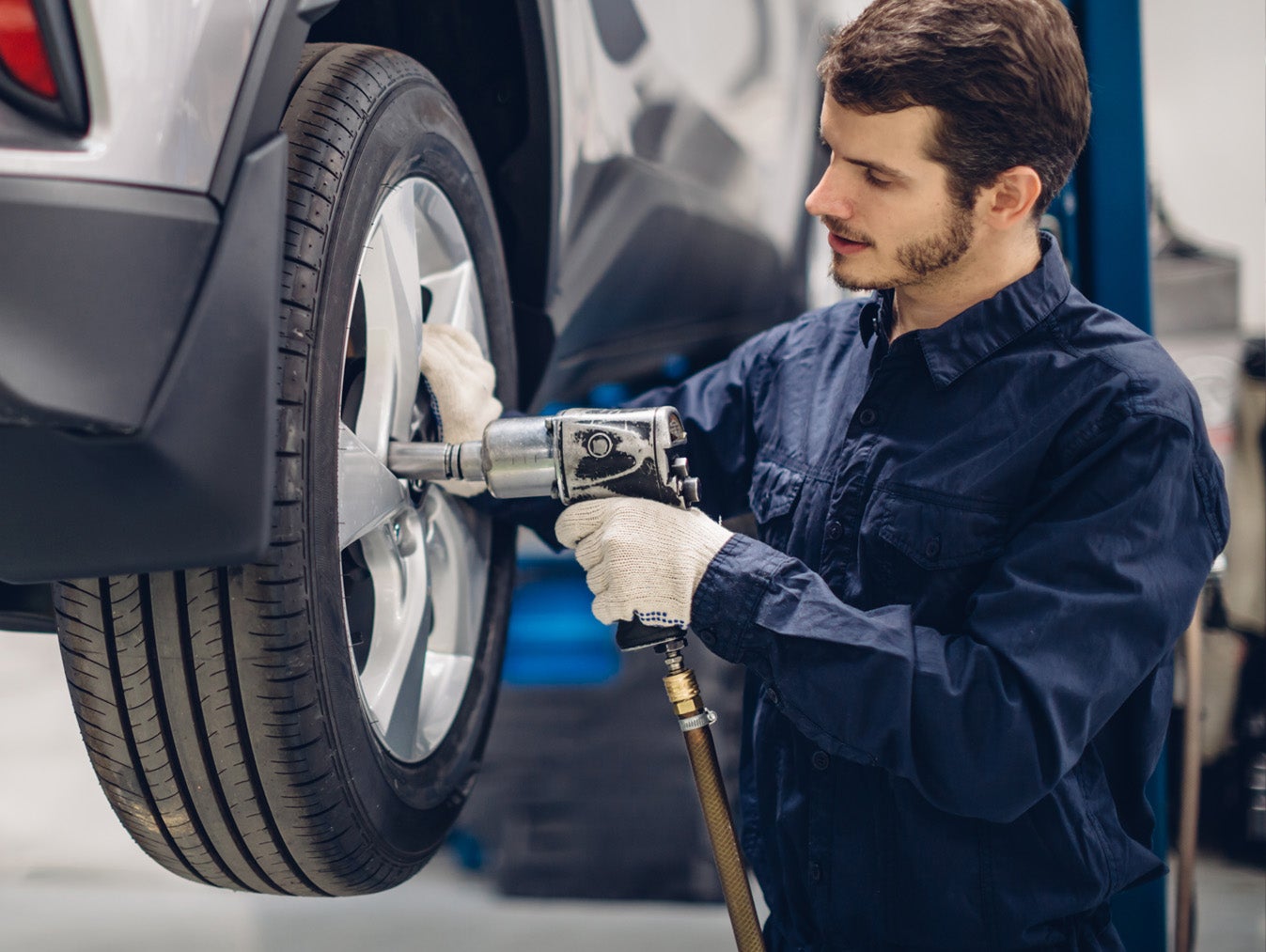 Mechanic using an impact wrench to remove or install a vehicle wheel during tire service.
